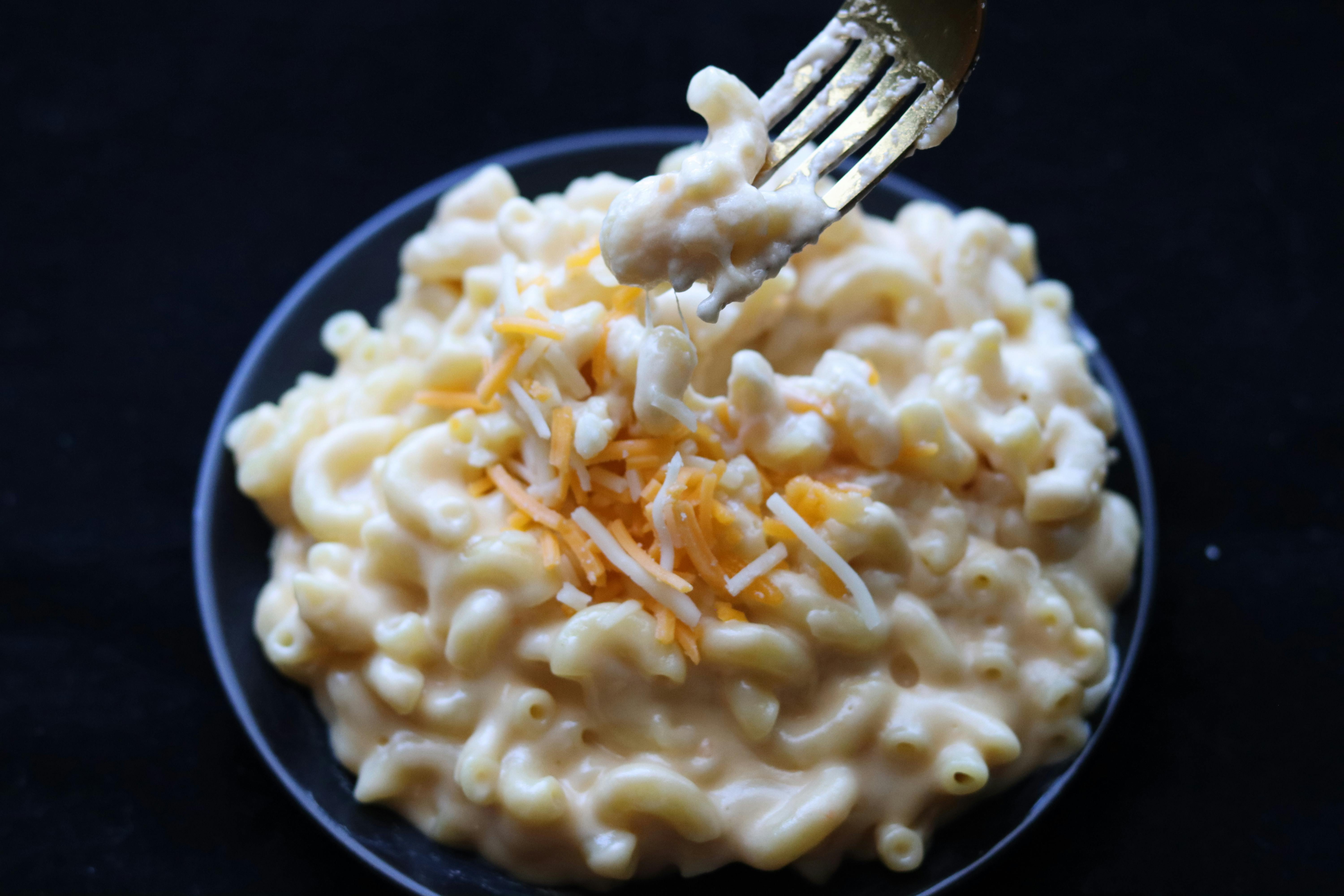 A photo of a fork in a bowl of mac and cheese 